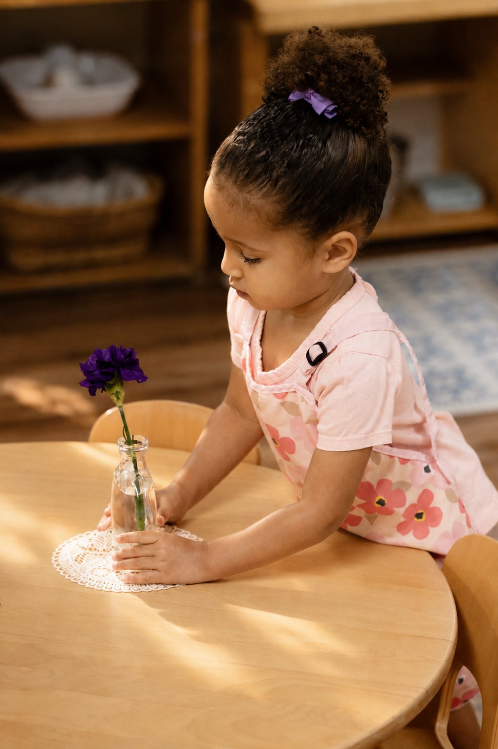 A young child arranging a flower in a bud vase