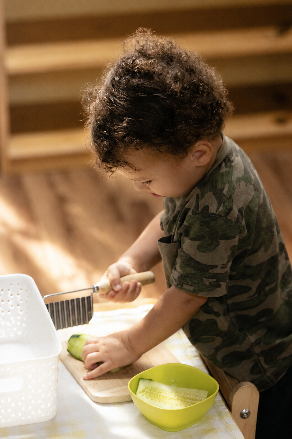 A young child slicing cucumber in the Youngest Children's Community